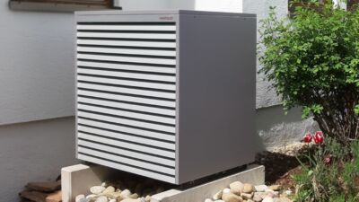 Graue Wärmepumpe an einem Gebäude